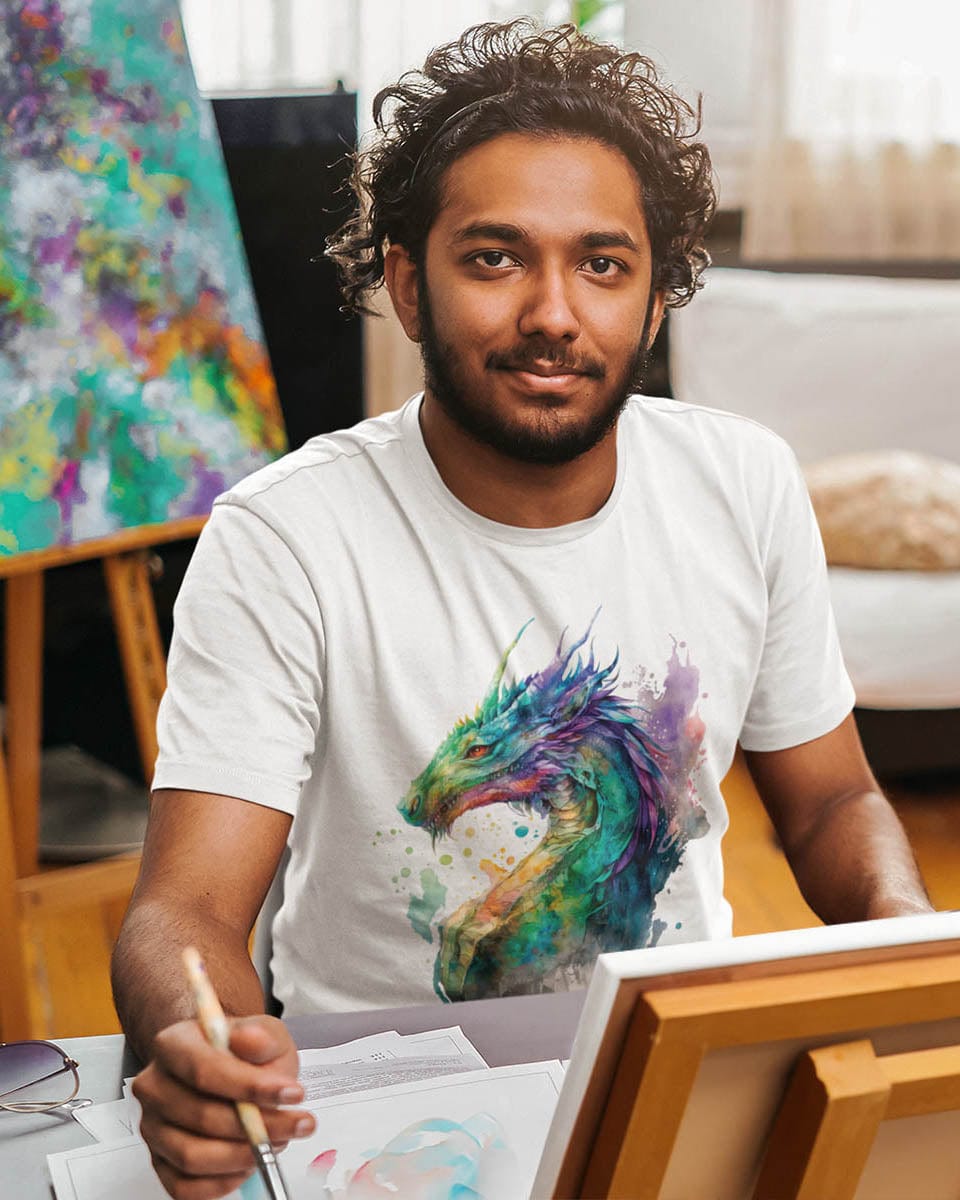 Male artist wearing Chromatic Sentinel shirt with a vibrant watercolor art design, holding a paintbrush in front of a canvas.