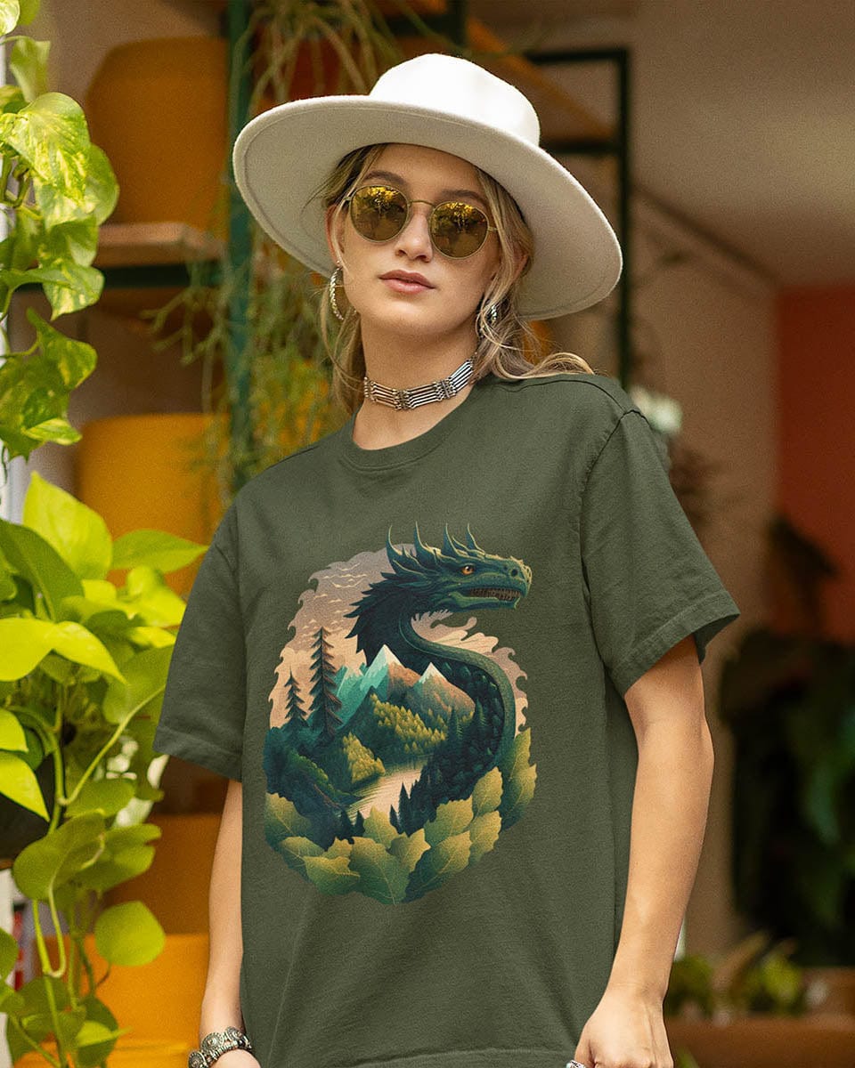 Woman standing outdoors among plants, wearing a Go Green Dragon shirt featuring a dragon blending into a mountain landscape.