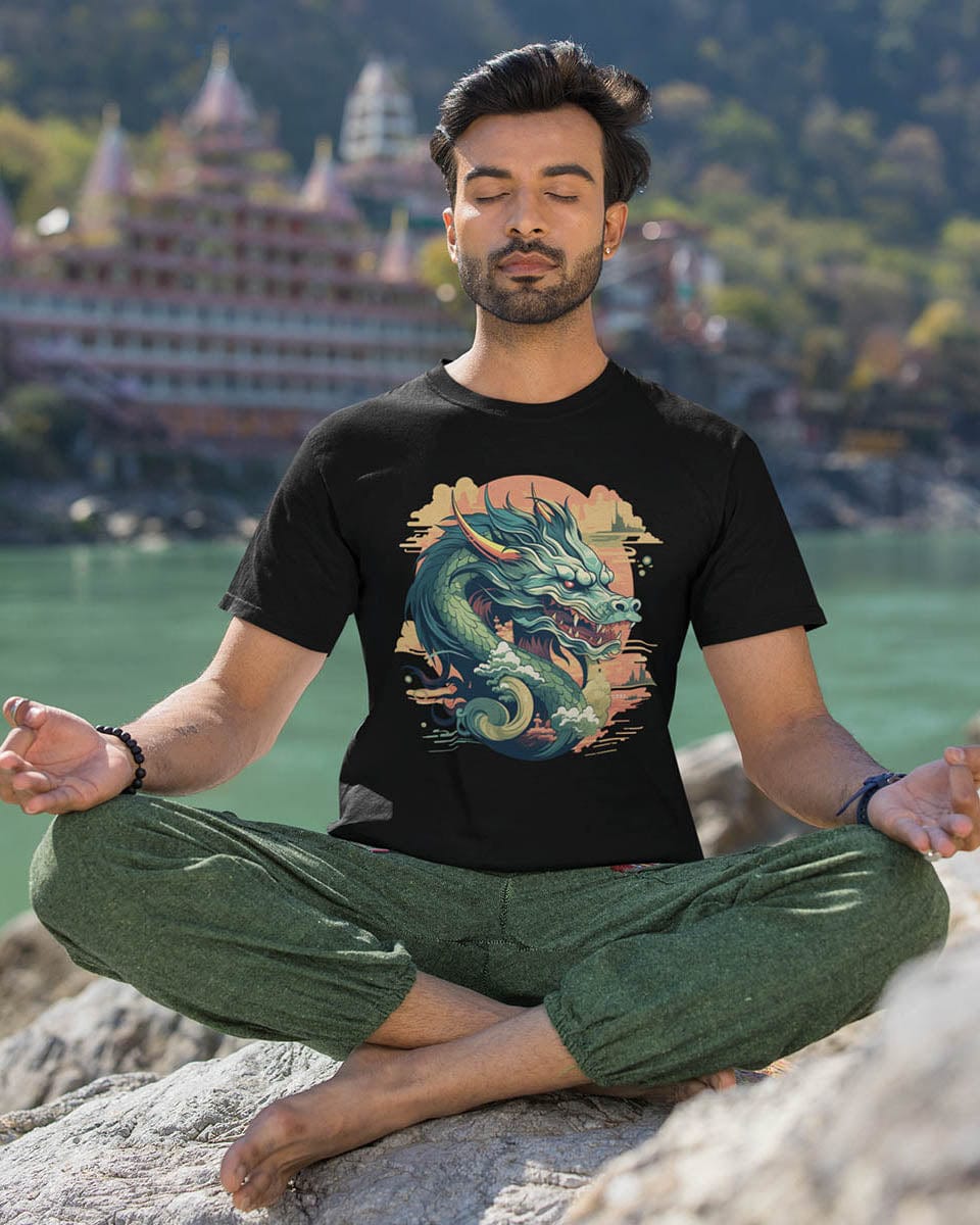 A meditating man wearing a Sunset Sovereign Dragon shirt featuring a jade-colored serpentine dragon in a golden sunset sky.