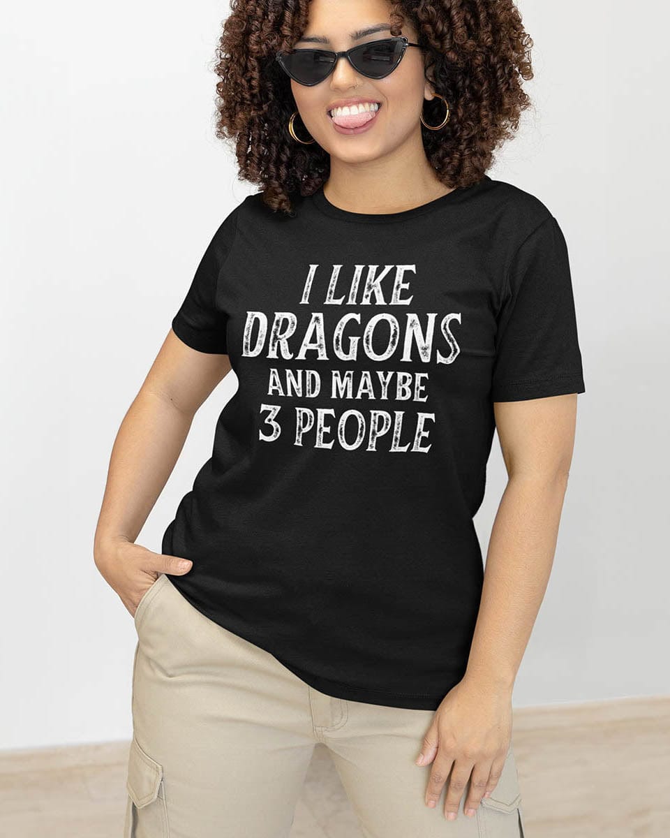 Woman wearing an I Like Dragons and Maybe 3 People shirt with distressed text, playfully sticking out her tongue.