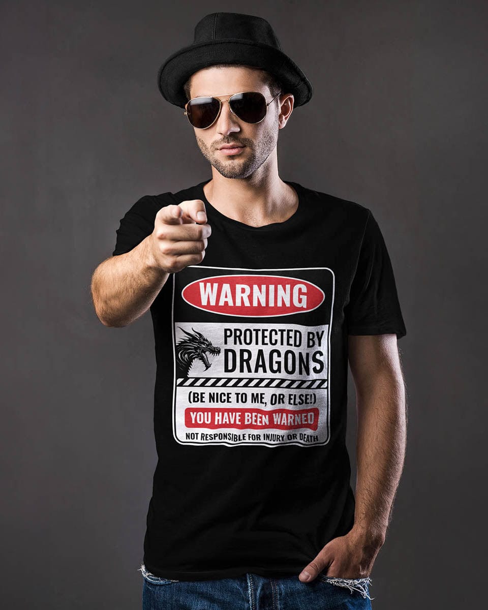Man pointing at the camera while wearing a Protected by Dragons shirt featuring a funny warning sign about dragons.