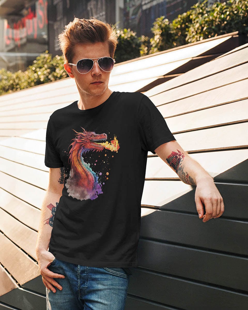 Man wearing a Blazing Fury shirt featuring watercolor art of a fire-breathing dragon, casually leaning on a wall outdoors.