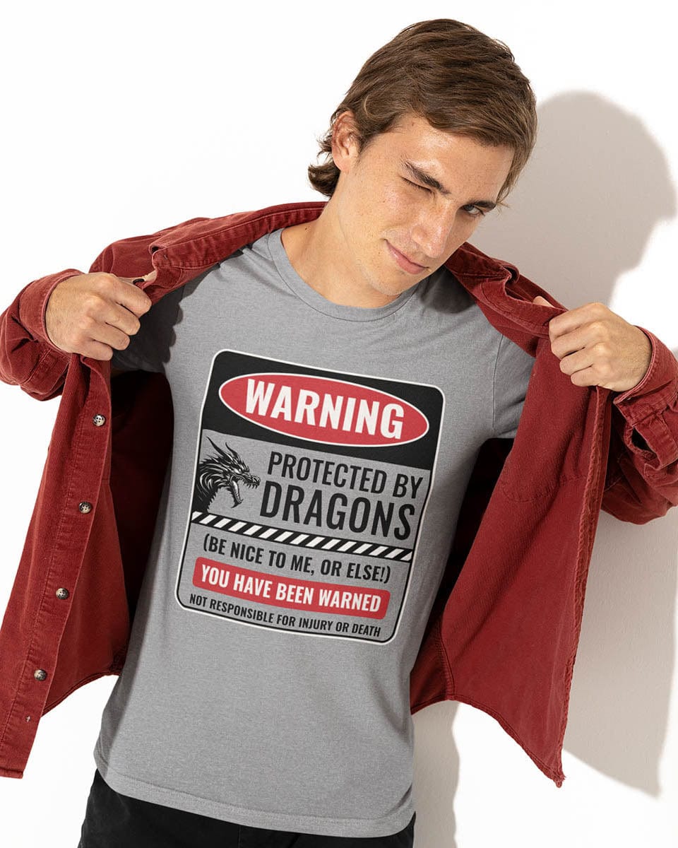 Man wearing a grey Protected by Dragons shirt, revealing the shirt by pulling open his red jacket while winking playfully.