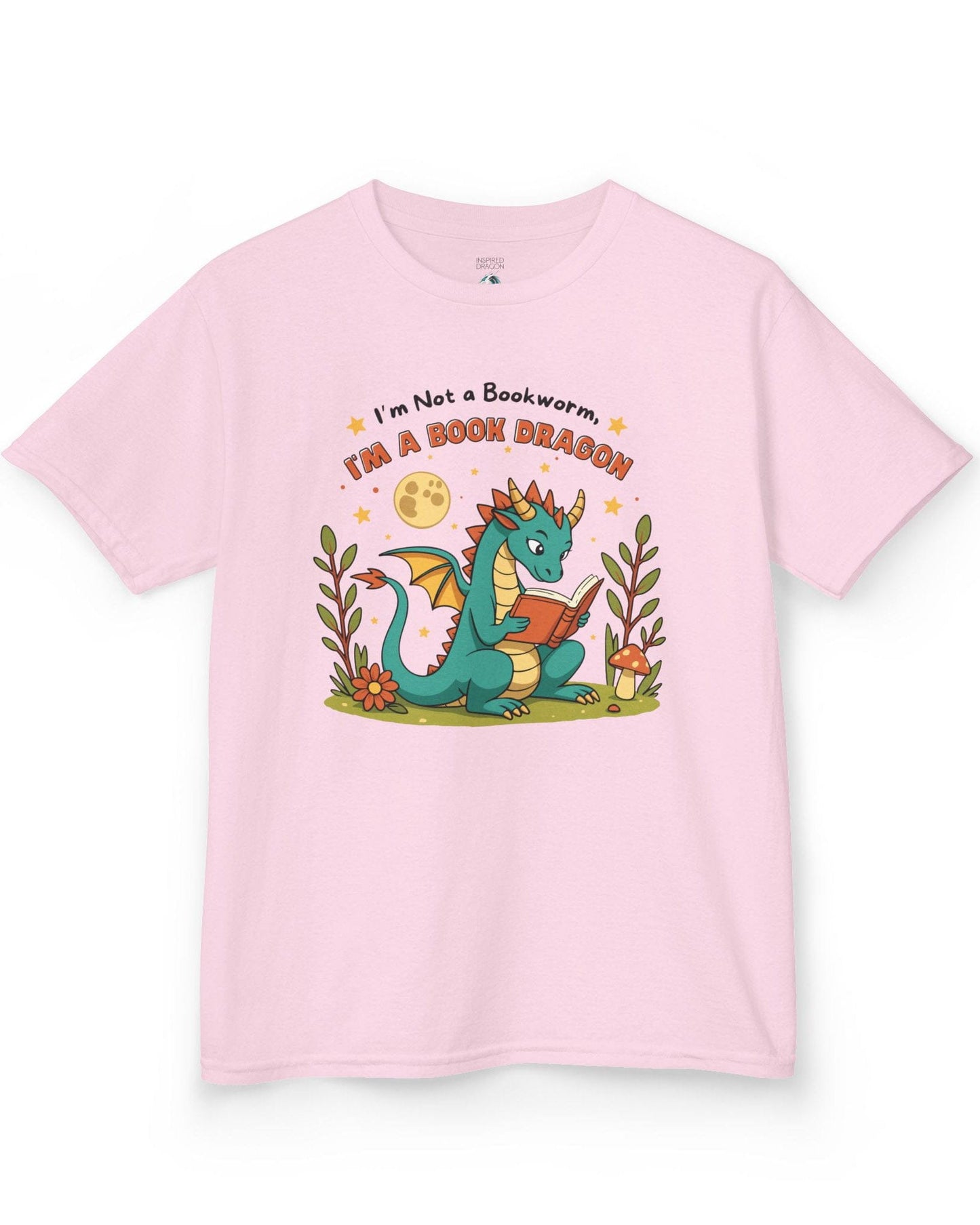 I'm a Book Dragon shirt in light pink featuring a teal dragon reading under the moonlight with plants and mushrooms.