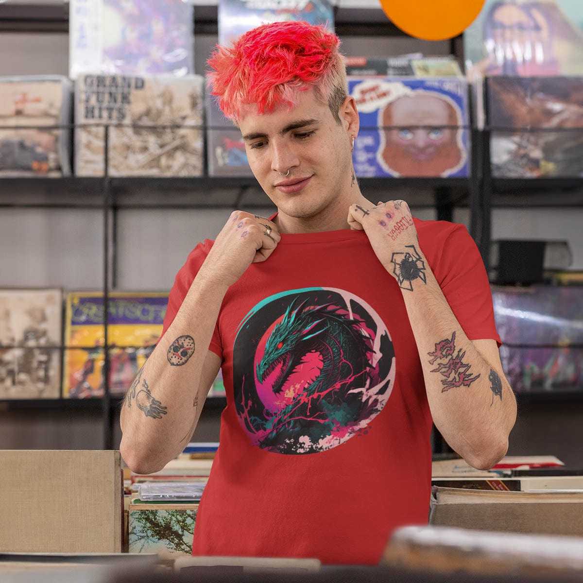 Tattooed man with red hair in a record store wearing an Angry Dragon Shirt featuring a fierce dragon with electric energy.