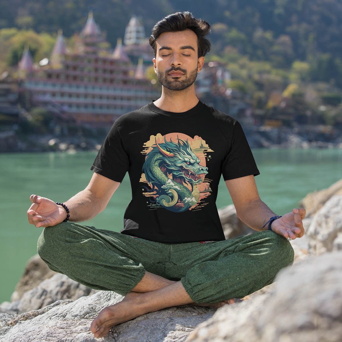 A meditating man wearing an Eastern Dragon Shirt featuring a jade-colored serpentine dragon floating in a golden sunset sky.