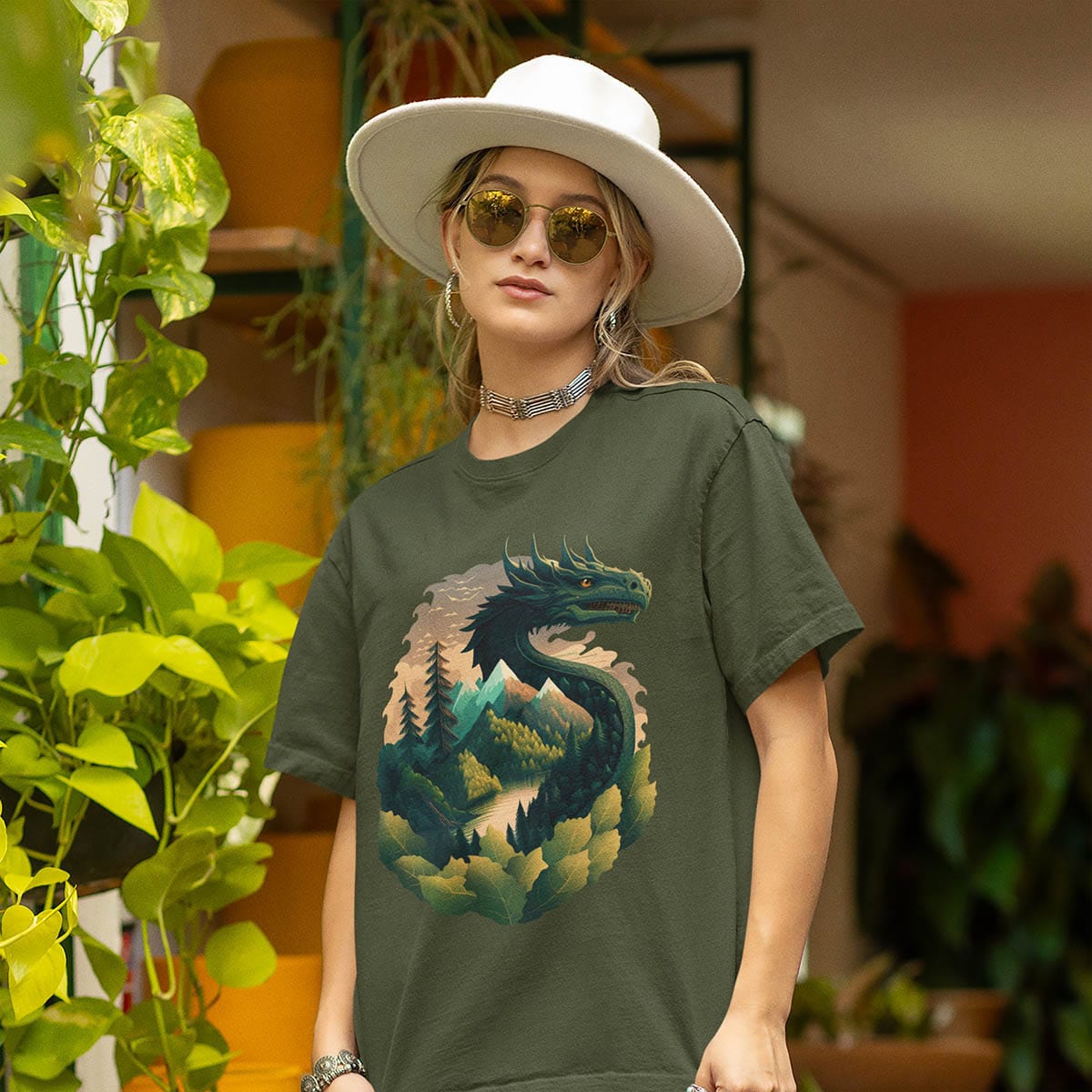 Woman standing outdoors among plants, wearing a Go Green Dragon Shirt featuring a dragon blending into a mountain landscape.