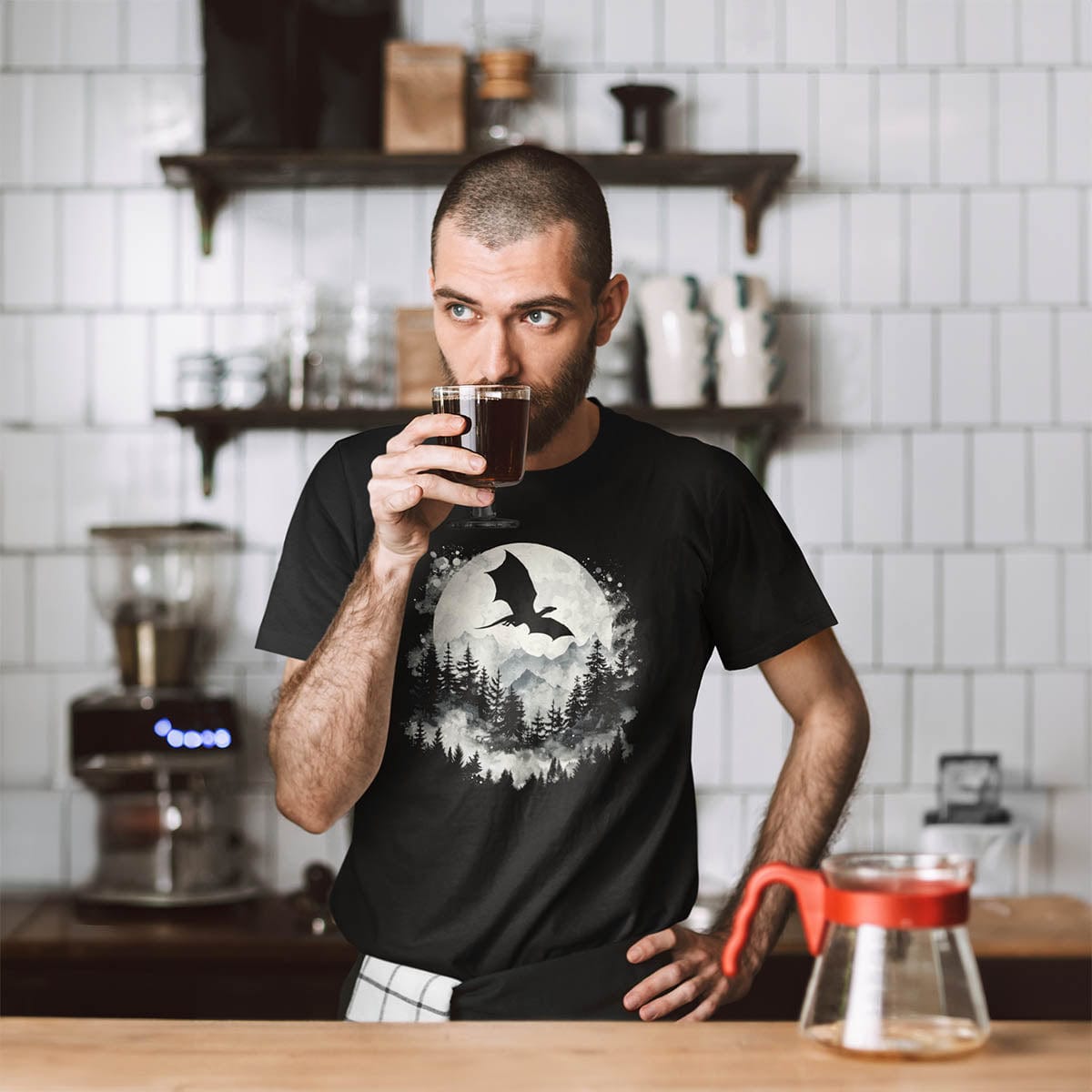 Barista enjoying a cup of coffee while wearing a Great Dragon Shirt featuring a dragon silhouette flying past a full moon.