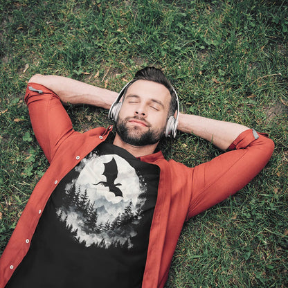 Man laying in the grass while wearing a Great Dragon Shirt featuring a flying dragon silhouette soaring past a full moon.