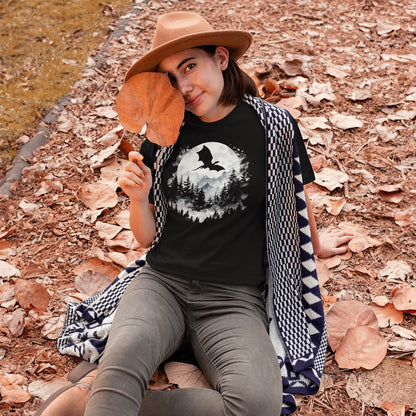 Woman sitting in fall leaves while wearing a Great Dragon Shirt featuring a dragon silhouette flying past a full moon.