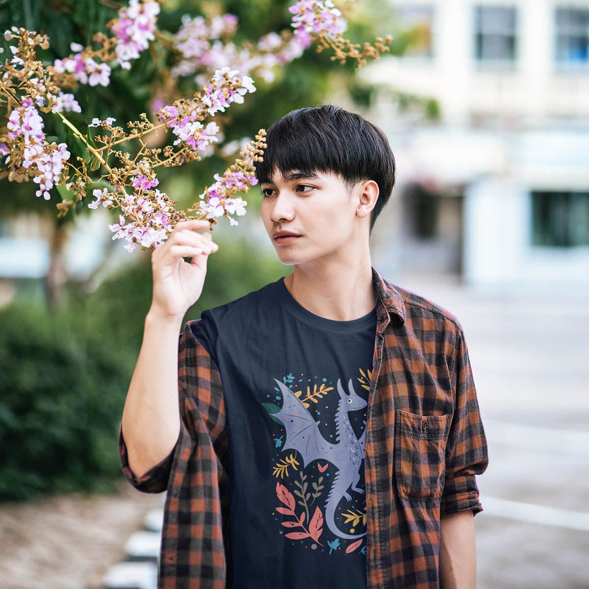 Man admiring flowers wearing a Nature Dragon Shirt featuring a whimsical flying dragon surrounded by leafy accents.